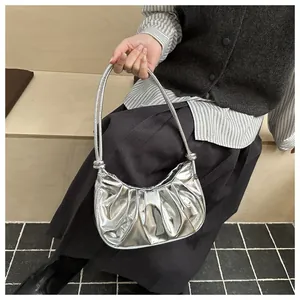 Détail du sac croissant argenté plissé avec finition métallique et longue poignée