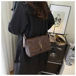 Detail of dark brown leather crossbody bag with elegant gold metal buckle and vintage design