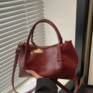 Deep red pleated faux leather handbag with handles and a long shoulder strap