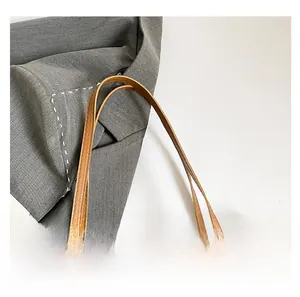 Détail de la poignée de sac marron avec coutures précises et motif monogramme chic