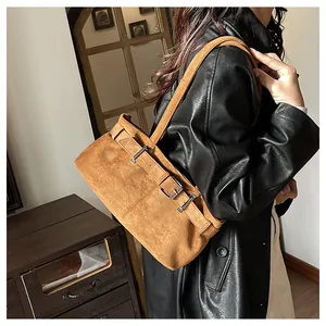 Detalle del bolso de hombro vintage de ante caramelo con hebillas y acabados plateados