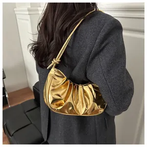 Détail du sac à bandoulière doré plissé avec bandoulière nouée sur un manteau gris