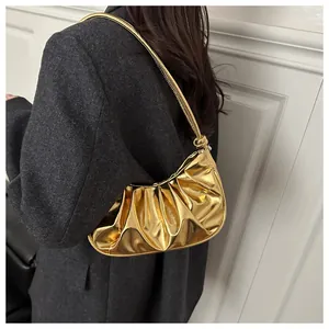 Détail du sac nuage plissé doré métallisé avec bandoulière nouée sur un blazer gris