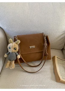 Détail du cabas en cuir mat marron avec plaque argentée et breloque lapin en peluche