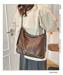 Detail of vintage brown leather tote bag with circular embossed HB logo and long strap