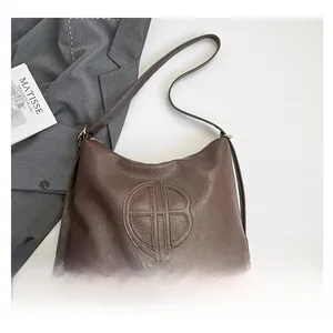Detail view of large brown faux leather tote featuring embossed HB logo and pebbled texture
