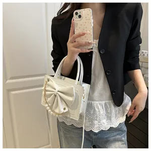 Détail du sac à main blanc avec nœud papillon en cuir et chaîne de perles chic