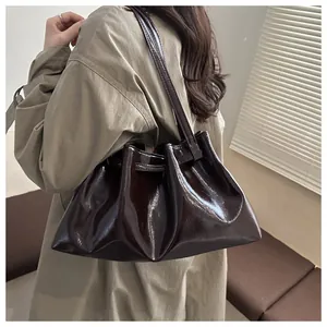 Detail einer dunkelbraunen, glänzenden Achseltasche mit Falten-Design am Model