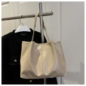 Detail of cream glossy leather tote bag with chain strap and vertical stitching accents