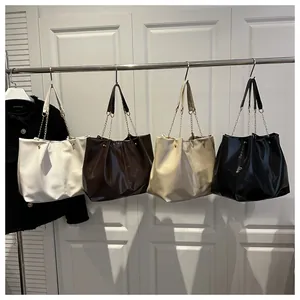 Detail showing high-capacity tote bags in four colors with gold chain straps and rivets