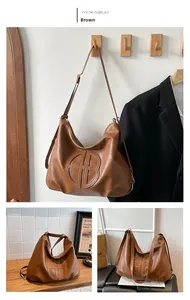 Detail of a large brown hobo bag showing pebbled leather texture and round gold hardware