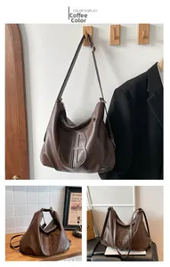 Detail of coffee brown leather hobo bag with embossed round logo and pebbled texture