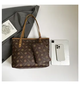 Close-up of brown printed tote bag showing repeated patterns and small matching pouch