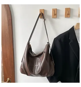 Detail view of large brown hobo bag featuring vintage texture and round embossed logo