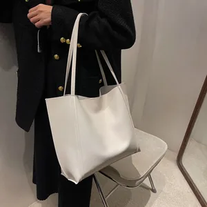 Side view of cream tote bag on shoulder showing its large capacity and matte leather texture