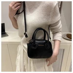 Detail der minimalistischen schwarzen Ledertasche mit goldener Aufschrift und Beschlägen