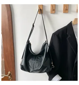 Detail of black tote bag with circular embossed stitching and adjustable leather strap