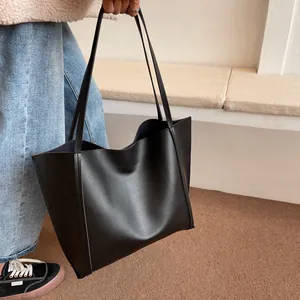 Detailed side view of the black oversized tote bag showing stitching and supple texture