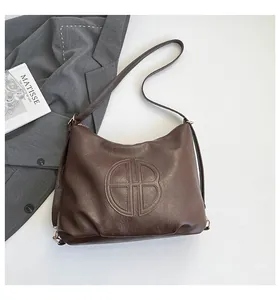 Detail view of large brown faux leather tote bag with embossed logo and pebble texture