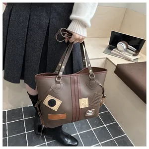 Detail of dark brown PU tote bag featuring vintage patches and versatile shoulder strap
