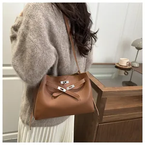 Nahaufnahme der karamellbraunen Ledertasche mit klassischem Metalldrehverschluss und Riemen