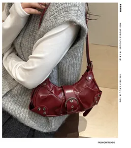 Sac bandoulière vintage rouge foncé avec rivets métalliques et boucle sur un mannequin