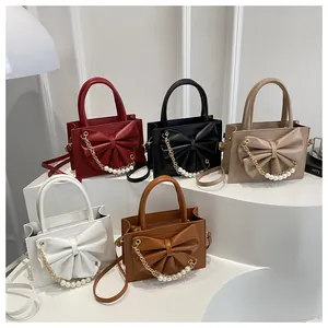 Détail de cinq couleurs de sacs à main carrés avec chaîne en perles et décoration nœud