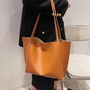 Detail view of large vintage caramel tote bag worn on shoulder with stitching detail