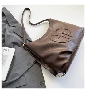 Detail of deep brown faux leather tote bag with circular geometric embossing on surface