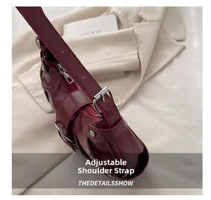 Détail de la bandoulière réglable et boucle en métal sur le sac à bandoulière rouge foncé