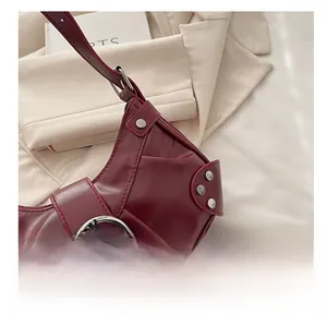 Détail d'un sac hobo bordeaux vintage avec grandes boucles métalliques et rivets argentés