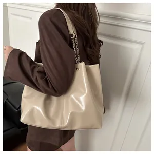 Detail of glossy beige tote bag featuring a chain strap and elegant vertical stitching