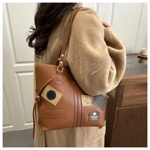 Detail view of brown PU leather tote bag with vintage patches and drawstring side accents