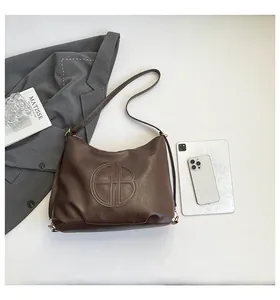 Close-up of dark brown pebble-grain leather tote with embossed logo and shoulder strap