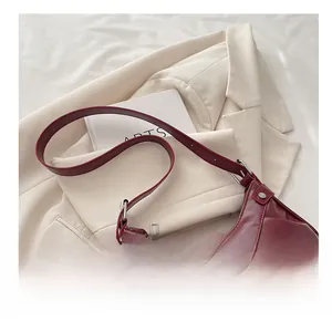 Détail du sac à épaule en cuir bordeaux avec clous argentés et boucle métallique