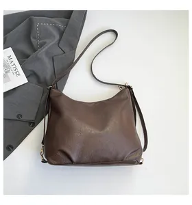 Detailed top view of a large brown leather tote bag with a gold metal buckle and strap