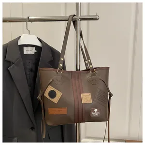 Detail of vintage brown patchwork tote bag with fashion letter patches and twin handles
