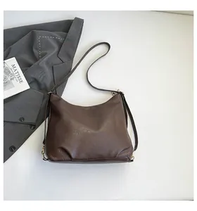 Close-up of deep brown hobo bag showing fine lychee texture and gold-tone zipper hardware