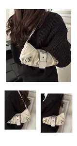 Detail view of cream canvas underarm bag featuring biker buckles and eyelet hardware