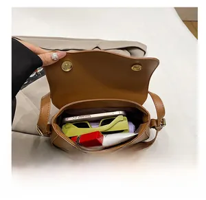 Vue intérieure du sac bandoulière marron montrant l'espace pour téléphone et maquillage