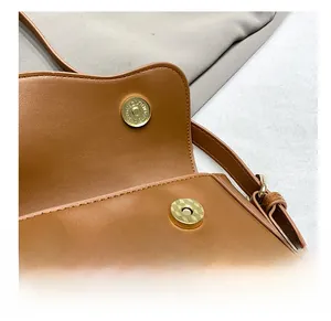 Détail de la boucle magnétique dorée sur le sac bandoulière en cuir marron