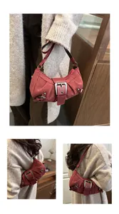 Detail view of burgundy moon-shaped underarm bag with decorative metal buckle and strap