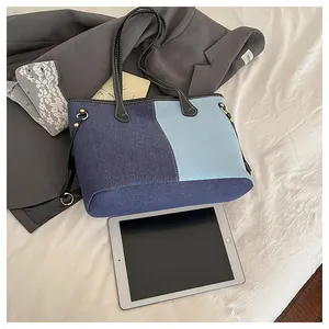 Detail of the blue denim patchwork tote bag with white stitching and leather handles