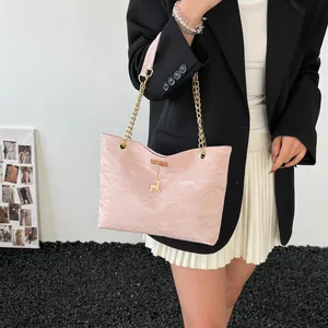 Detail of pink pleated tote bag with gold chain strap and deer charm on black blazer
