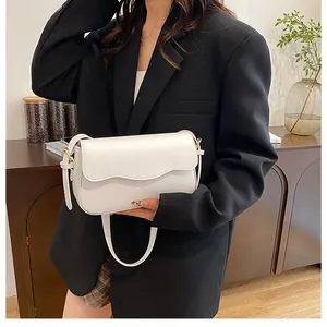 Sac à bandoulière blanc minimaliste avec rabat ondulé porté par un mannequin chic