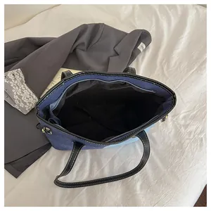 Internal view of denim tote bag with spacious compartment, black lining and zipper pocket