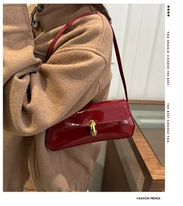 Detalle del bolso de hombro en charol rojo con hebilla de cierre de metal dorado en U