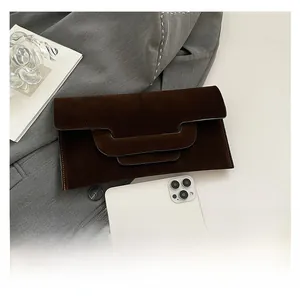 Detail of dark brown suede clutch featuring a three-tier wave flap and visible stitching