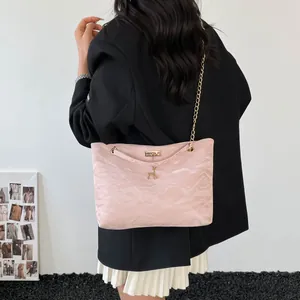 Pink shoulder bag detail with gold chain strap and deer pendant on pleated fabric