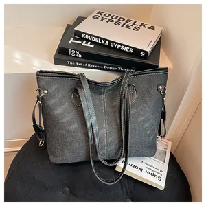 Detail of dark denim tote bag with black leather handles and gold rivet accents